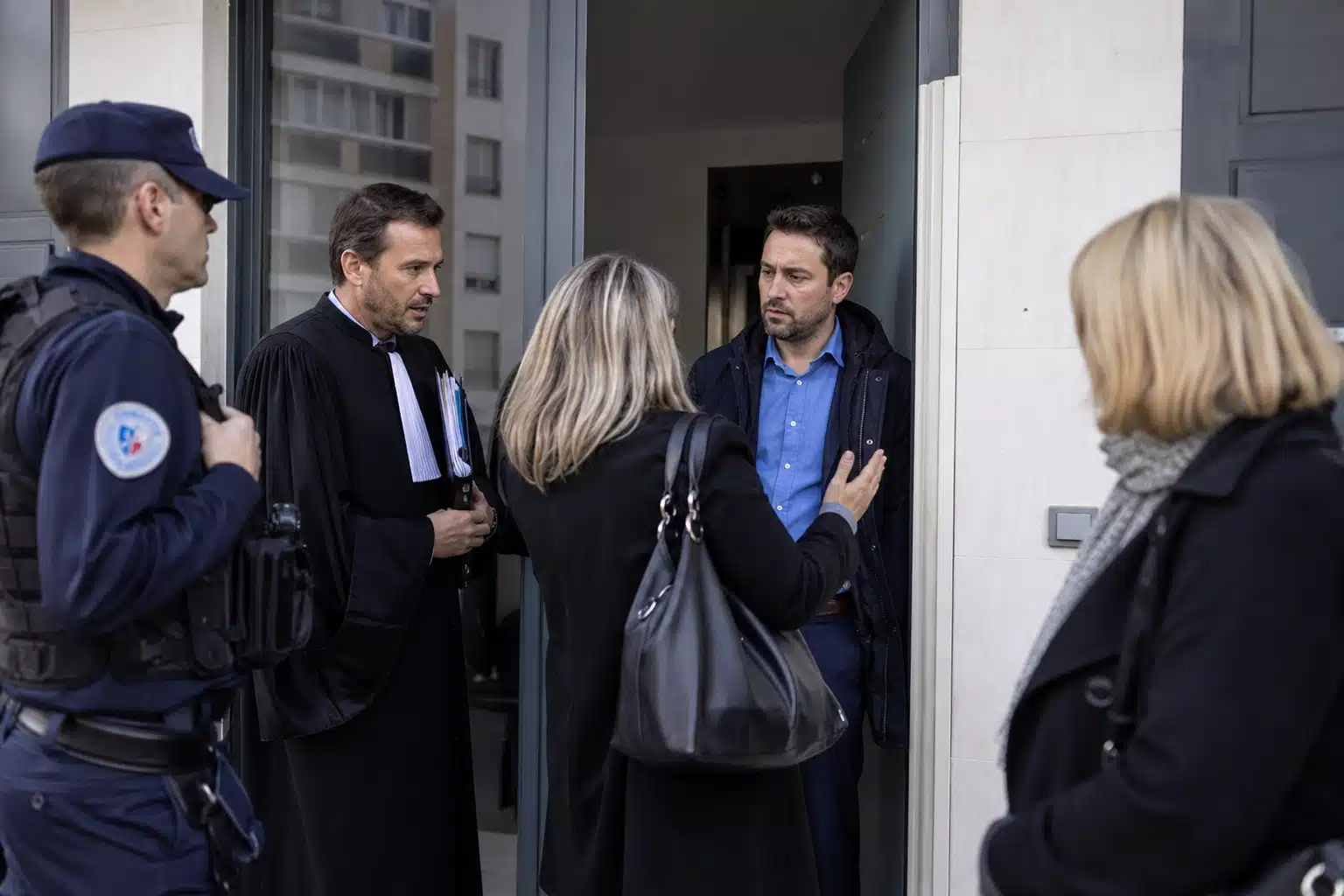 Quatre personnes discutant dans un couloir de bureau
